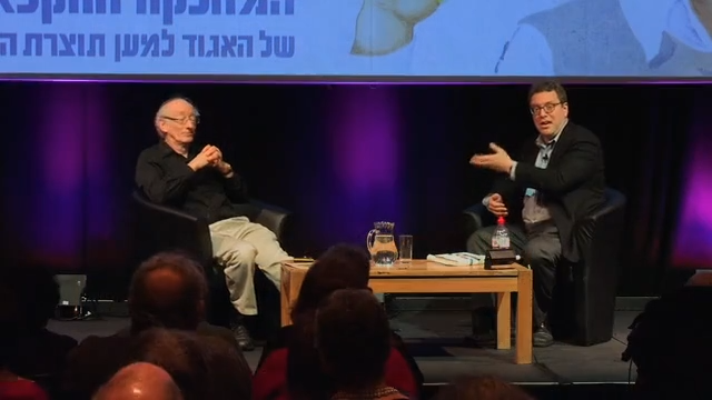 Two men sit on stage