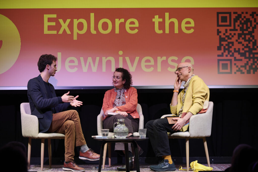Two men and a women sit on stage at festival, live event, sitting in chairs