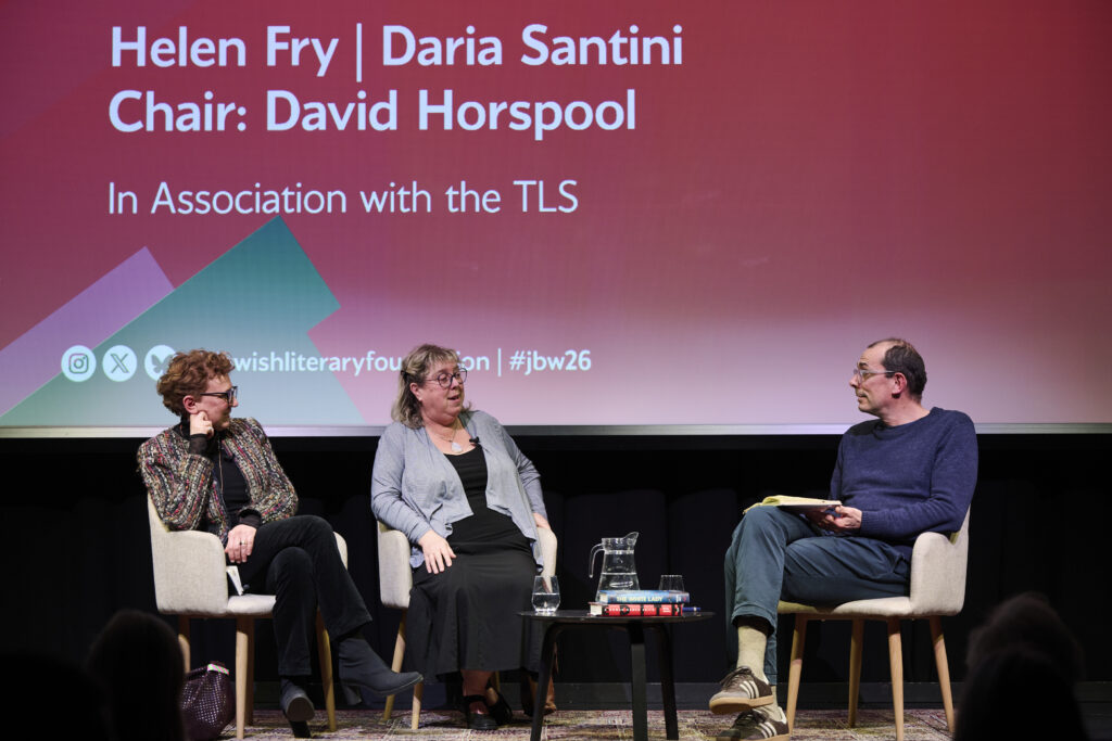 three people talking to each other, two women and one man, sitting in white chairs